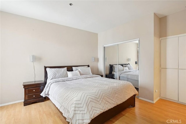 bedroom featuring baseboards, light wood-style flooring, and a closet