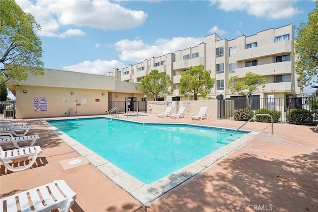 community pool with a patio and fence