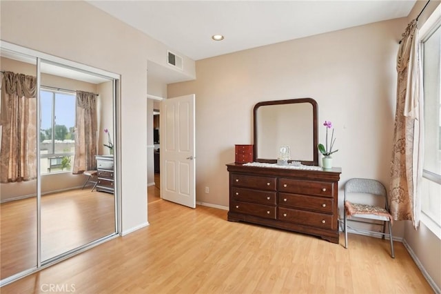 bedroom featuring baseboards, visible vents, multiple windows, and light wood-style floors