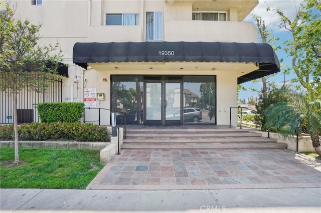 view of exterior entry featuring french doors and stucco siding