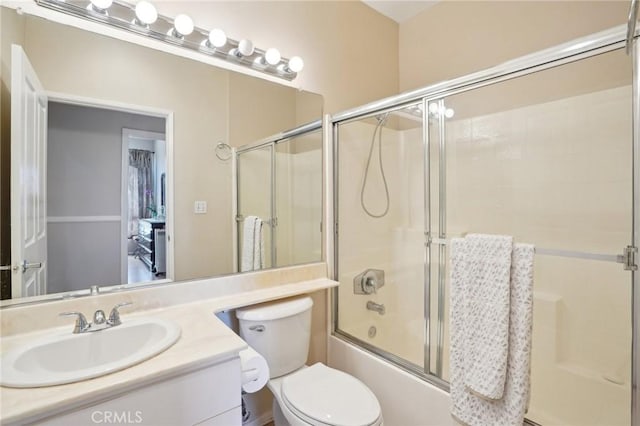 bathroom featuring vanity, enclosed tub / shower combo, and toilet