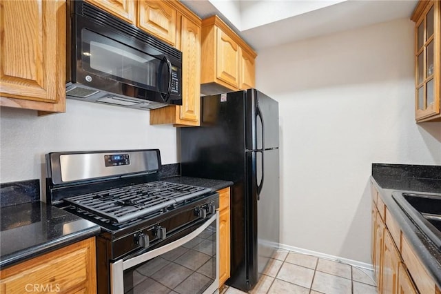 kitchen featuring black microwave, stainless steel gas stove, baseboards, glass insert cabinets, and light tile patterned flooring