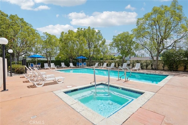 pool with fence, a community hot tub, and a patio area