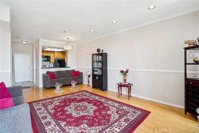living area featuring light wood-style floors, baseboards, ornamental molding, and recessed lighting