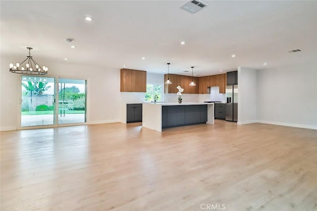 kitchen featuring stainless steel refrigerator with ice dispenser, open floor plan, plenty of natural light, and visible vents