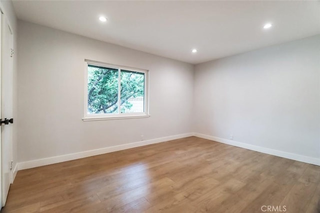 empty room featuring recessed lighting, baseboards, and light wood-style floors