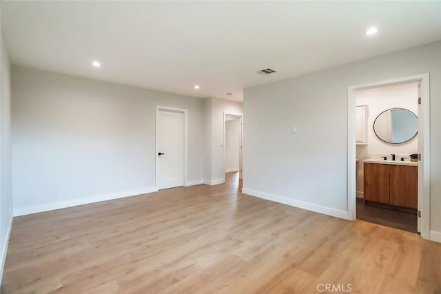 empty room featuring recessed lighting, a sink, and light wood-style floors