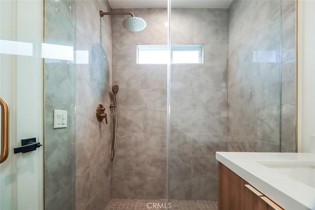 bathroom featuring tiled shower and vanity