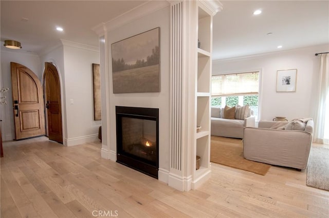 living room with a glass covered fireplace, ornamental molding, recessed lighting, and wood finished floors