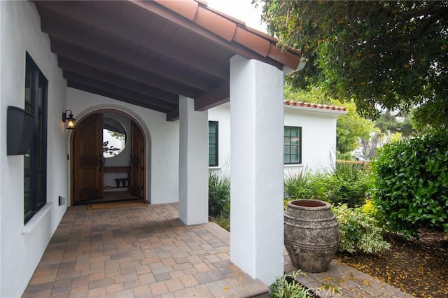 view of exterior entry featuring stucco siding and a tiled roof