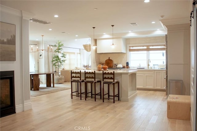 kitchen with a center island, a sink, light countertops, light wood finished floors, and a breakfast bar