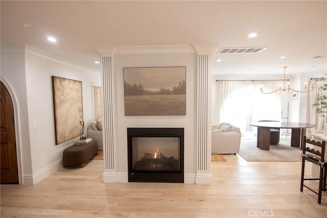 interior space featuring crown molding, a warm lit fireplace, light wood finished floors, arched walkways, and visible vents