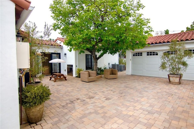 view of patio with decorative driveway, a garage, and central air condition unit