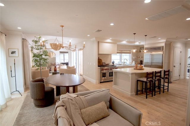 kitchen featuring visible vents, light wood-style floors, a breakfast bar area, high quality appliances, and recessed lighting