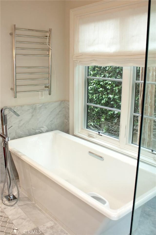 full bath with marble finish floor, a freestanding tub, and radiator heating unit