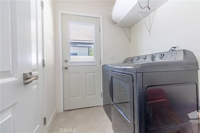 washroom featuring laundry area, baseboards, washing machine and dryer, and light tile patterned flooring