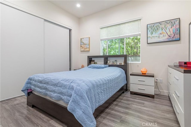 bedroom with recessed lighting, baseboards, wood finished floors, and a closet