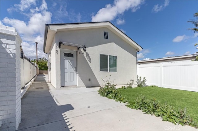 back of house featuring a lawn, a patio area, stucco siding, and fence