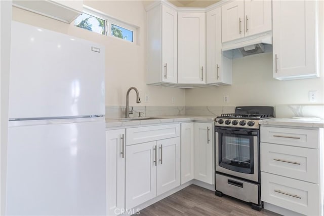 kitchen with stainless steel gas range, a sink, freestanding refrigerator, white cabinetry, and under cabinet range hood