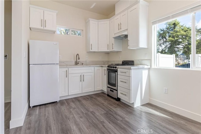 kitchen featuring freestanding refrigerator, stainless steel range with gas cooktop, white cabinetry, under cabinet range hood, and a sink