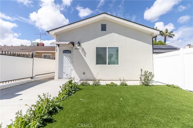 view of front of house featuring fence, a front yard, and stucco siding