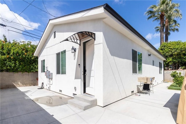 rear view of house featuring crawl space, fence, a patio area, and stucco siding