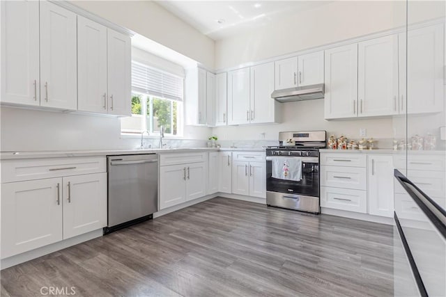 kitchen with light wood-type flooring, light countertops, under cabinet range hood, white cabinets, and stainless steel appliances
