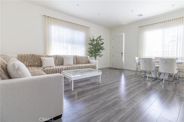 living area with visible vents, baseboards, and wood finished floors
