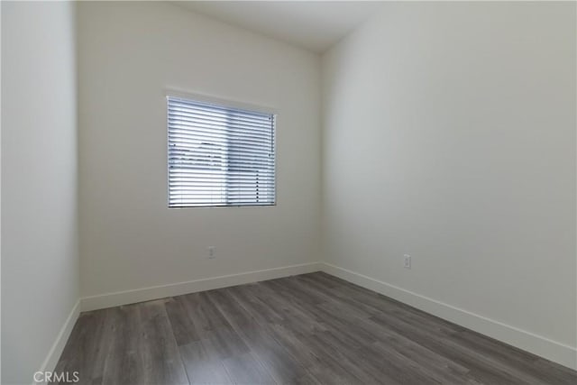 empty room featuring baseboards and dark wood-type flooring