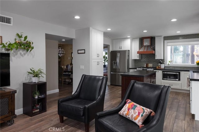 11080 Kayjay St, Riverside, CA 92503 - kitchen with stainless steel appliances, wall chimney range hood, dark countertops, a kitchen island, and dark wood finished floors