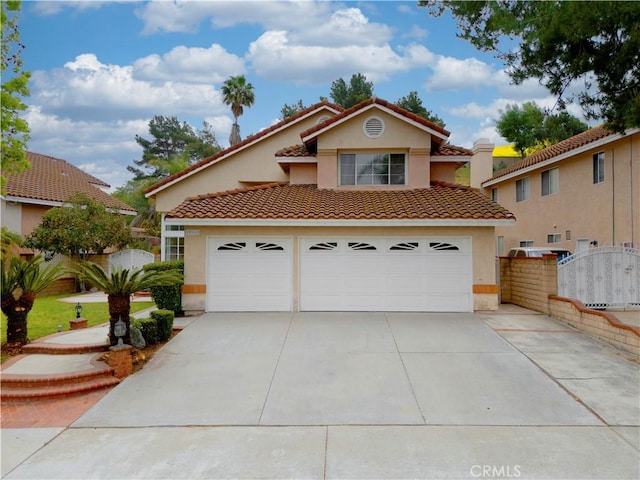 mediterranean / spanish house with a tiled roof, fence, driveway, and stucco siding