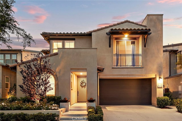 mediterranean / spanish-style home featuring an attached garage, a balcony, and stucco siding