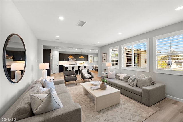 living room featuring recessed lighting, baseboards, visible vents, and light wood-style floors