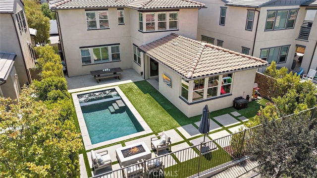 rear view of house featuring a patio, a fire pit, a tile roof, and stucco siding