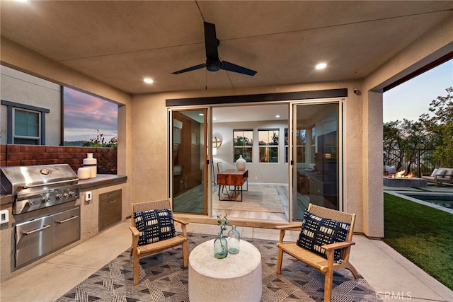 view of patio / terrace featuring grilling area, an outdoor kitchen, ceiling fan, and fence