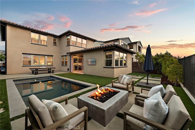 back of property featuring an outdoor pool, a fenced backyard, an outdoor living space with a fire pit, a patio, and stucco siding