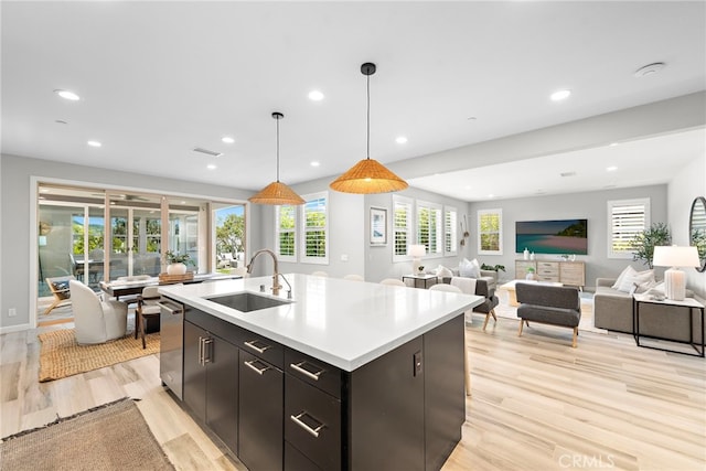 kitchen with a sink, light countertops, light wood-style floors, recessed lighting, and an island with sink