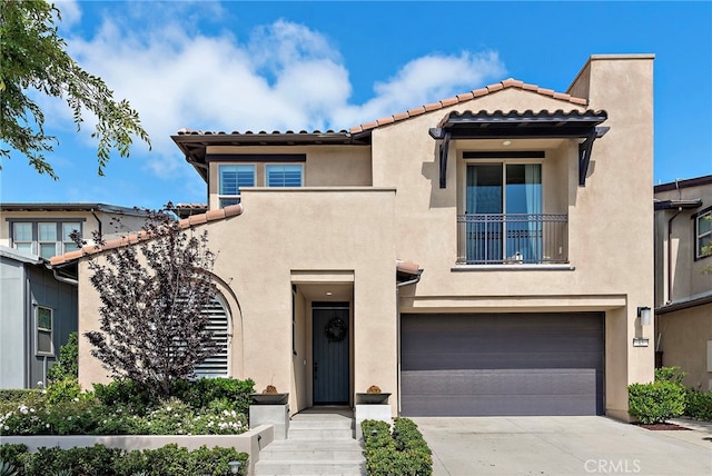 mediterranean / spanish home featuring an attached garage, stucco siding, a tiled roof, and concrete driveway