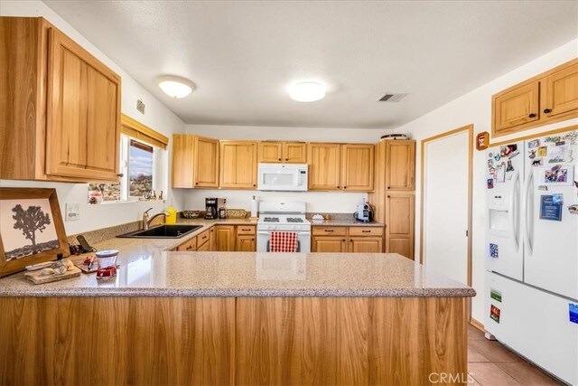 kitchen featuring light stone counters, a sink, white appliances, a peninsula, and visible vents