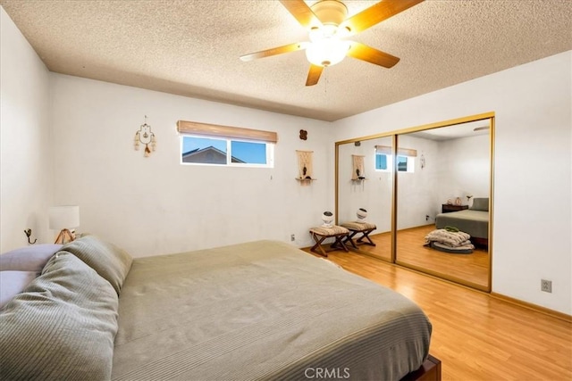 bedroom featuring light wood-type flooring, a textured ceiling, ceiling fan, and a closet