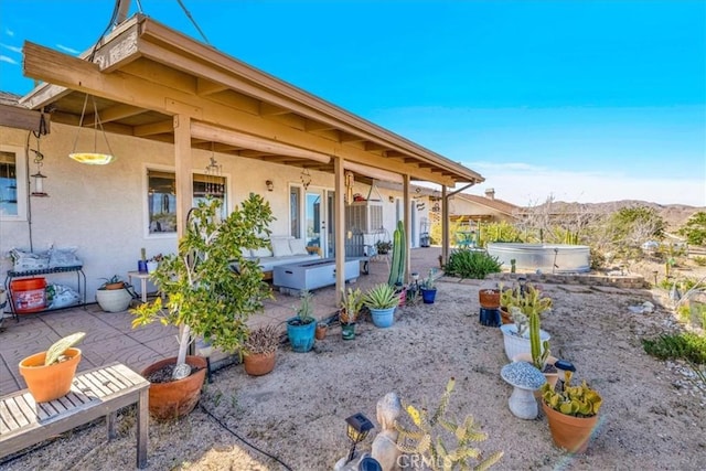 exterior space with a patio, a hot tub, stucco siding, and a mountain view