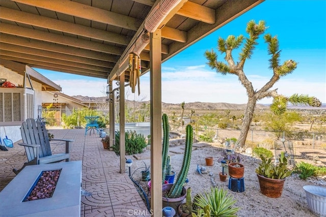 view of patio / terrace with an outdoor fire pit, a mountain view, and fence