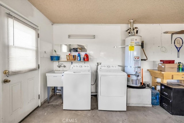 clothes washing area with strapped water heater, a textured ceiling, and washing machine and clothes dryer