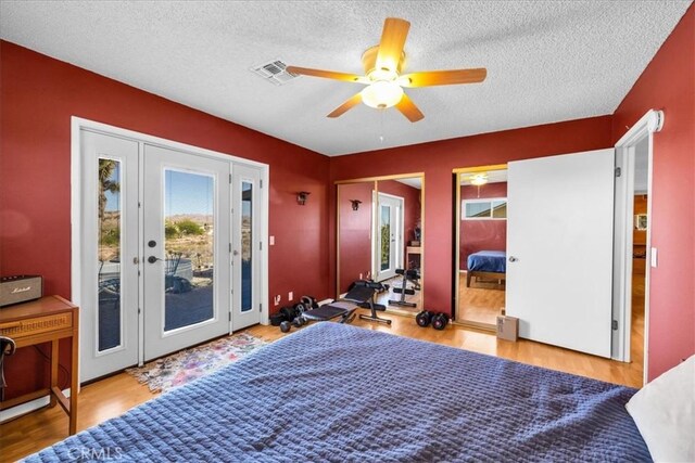 bedroom with a textured ceiling, wood finished floors, and access to exterior