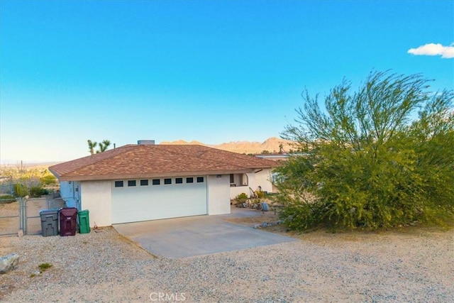 single story home featuring a garage, fence, stucco siding, a gate, and a mountain view