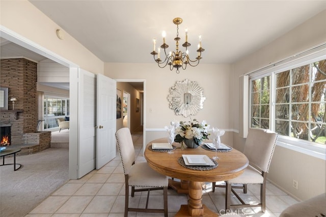 dining area with an inviting chandelier, light tile patterned floors, a wealth of natural light, and a fireplace