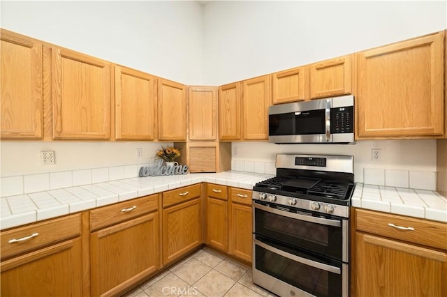 40949 Granite St, Palmdale, CA 93551 - kitchen with light tile patterned flooring, tile counters, and appliances with stainless steel finishes