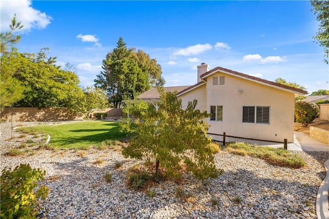 40949 Granite St, Palmdale, CA 93551 - view of side of property featuring a lawn, fence, a chimney, and stucco siding