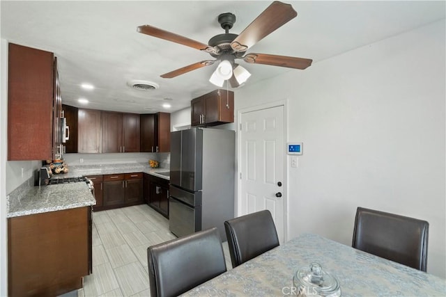 2113 Herrington Ave, San Bernardino, CA 92411 - kitchen with a ceiling fan, visible vents, appliances with stainless steel finishes, dark brown cabinets, and light stone counters