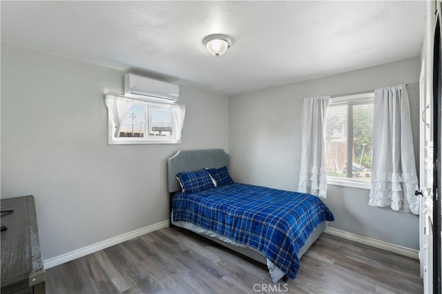 2113 Herrington Ave, San Bernardino, CA 92411 - bedroom featuring baseboards, a wall unit AC, and wood finished floors